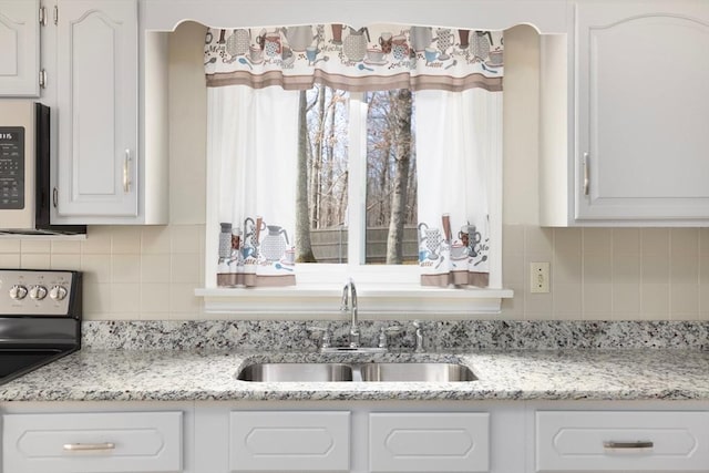 kitchen featuring a sink, stainless steel appliances, decorative backsplash, and white cabinetry