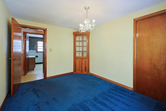 carpeted empty room with a notable chandelier