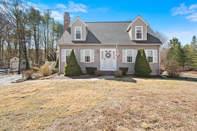 new england style home with a front yard and roof with shingles