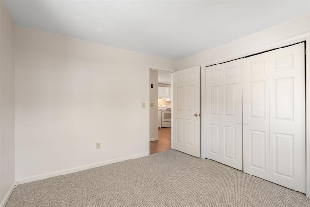 unfurnished bedroom with light carpet and a closet