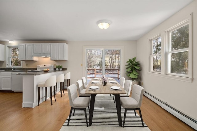 dining space featuring sink, light hardwood / wood-style flooring, and baseboard heating