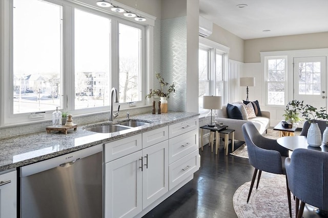 kitchen with dark hardwood / wood-style floors, white cabinetry, sink, stainless steel dishwasher, and light stone countertops