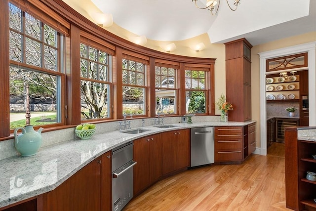 bar featuring stainless steel dishwasher, vaulted ceiling, and light wood-style flooring