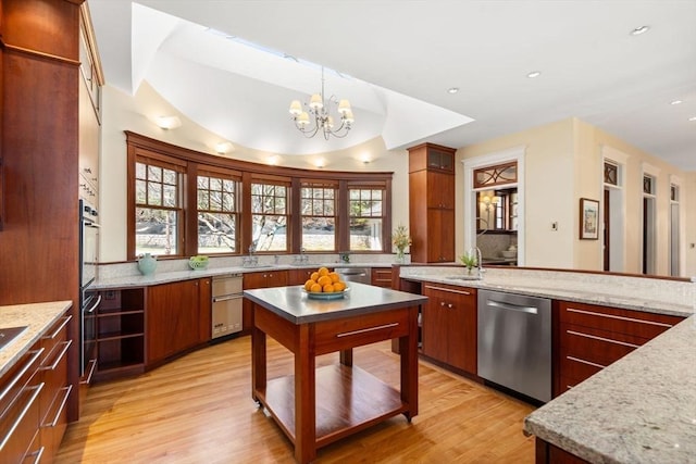 kitchen with stainless steel dishwasher, light wood-style flooring, a sink, a notable chandelier, and decorative light fixtures