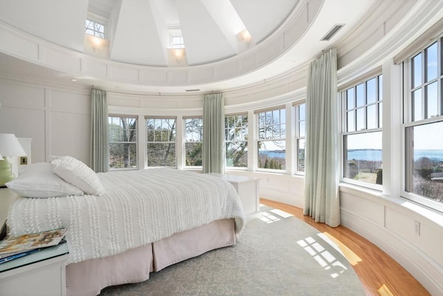 bedroom with a decorative wall, multiple windows, and visible vents