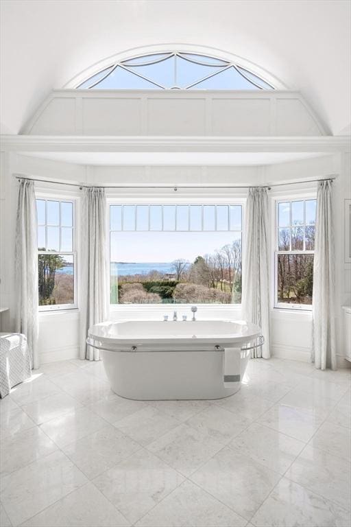 full bath with a soaking tub, marble finish floor, and plenty of natural light