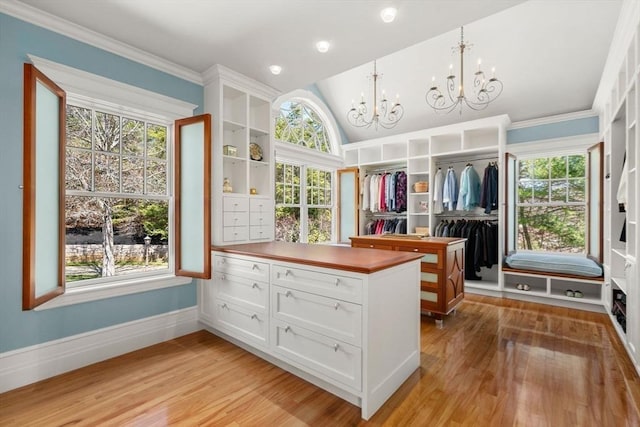 walk in closet featuring light wood-style floors, vaulted ceiling, and an inviting chandelier