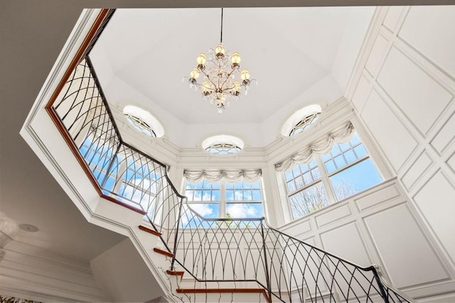 interior space featuring stairs, a notable chandelier, and a towering ceiling