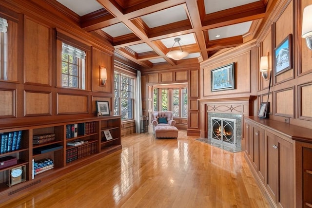 sitting room featuring a decorative wall, light wood-style floors, beamed ceiling, a premium fireplace, and coffered ceiling