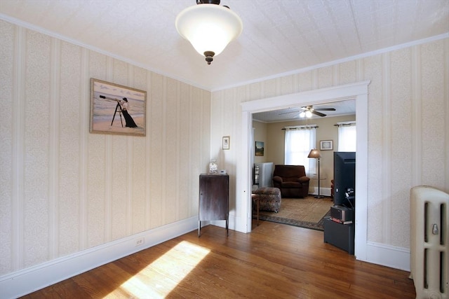 interior space featuring wood finished floors, crown molding, and wallpapered walls