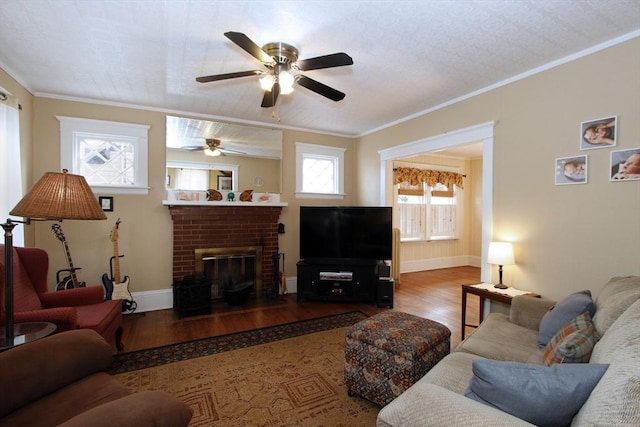 living room featuring wood-type flooring, a brick fireplace, ornamental molding, and ceiling fan