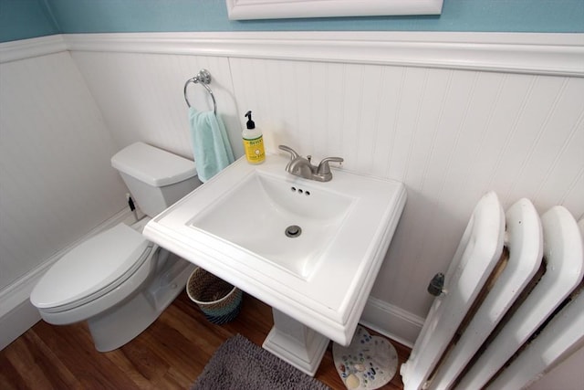 bathroom with a wainscoted wall, toilet, and wood finished floors