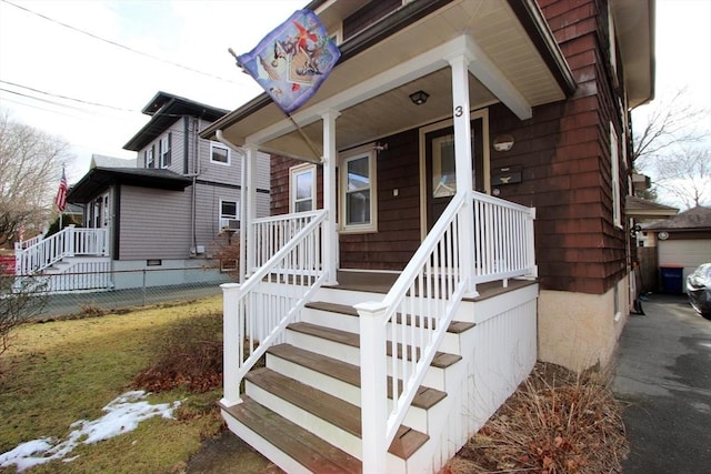 view of exterior entry with covered porch and fence