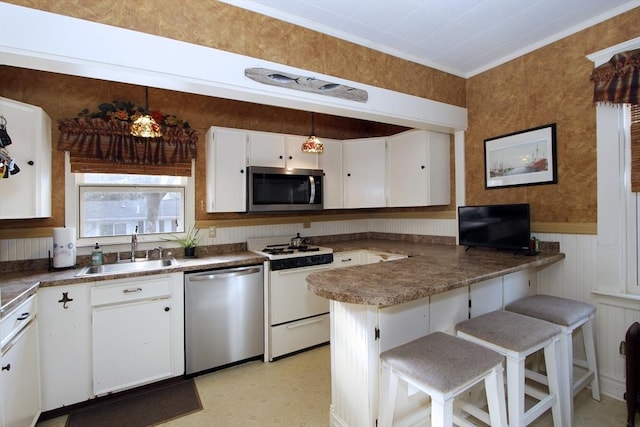 kitchen featuring appliances with stainless steel finishes, pendant lighting, sink, white cabinets, and a kitchen breakfast bar