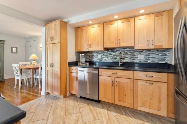 kitchen with stainless steel appliances, a sink, recessed lighting, dark countertops, and decorative backsplash