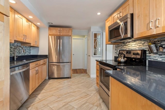 kitchen featuring stainless steel appliances, a sink, recessed lighting, tasteful backsplash, and light brown cabinets