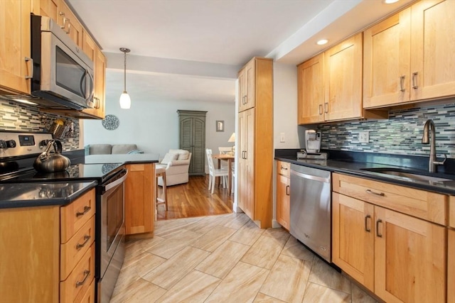 kitchen with stainless steel appliances, a sink, dark countertops, decorative backsplash, and recessed lighting