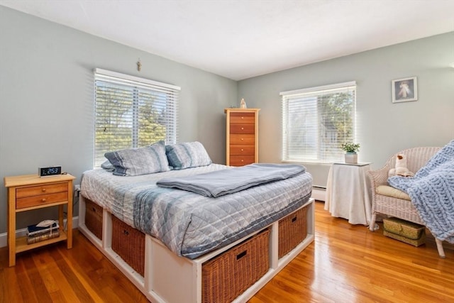 bedroom with wood finished floors and baseboard heating