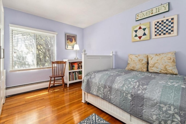 bedroom with a baseboard radiator and wood finished floors