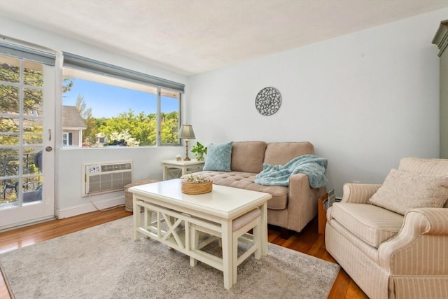 living room with a wall mounted AC, wood finished floors, and plenty of natural light