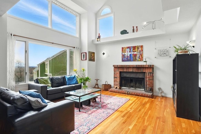 living area with light wood finished floors, a fireplace, and a towering ceiling