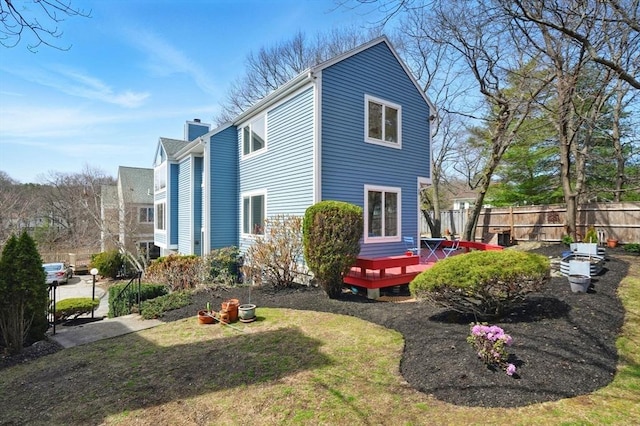 exterior space featuring fence, a wooden deck, and a chimney