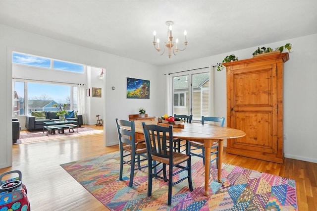 dining room featuring baseboards, light wood-type flooring, and an inviting chandelier