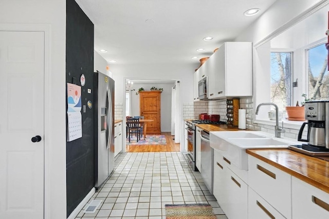 kitchen with plenty of natural light, white cabinetry, decorative backsplash, and appliances with stainless steel finishes