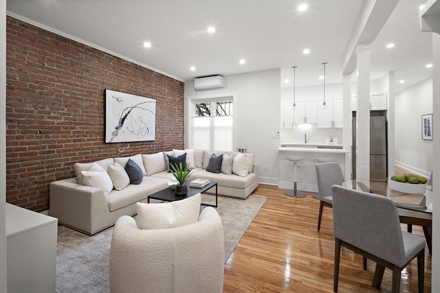 living area featuring brick wall, a wall mounted AC, light wood-style flooring, and recessed lighting