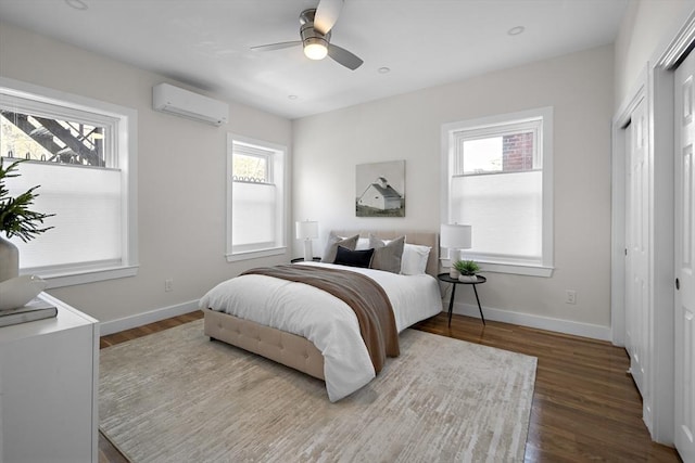 bedroom featuring a wall unit AC, wood finished floors, and multiple windows
