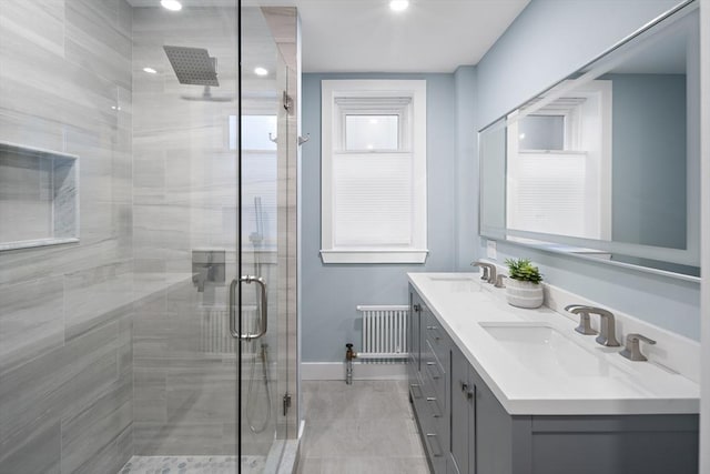 bathroom featuring a sink, double vanity, a stall shower, radiator, and recessed lighting