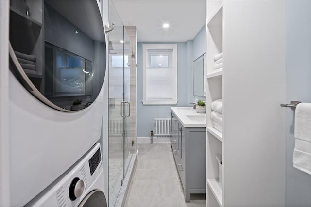 laundry area with stacked washer and clothes dryer, baseboards, radiator, recessed lighting, and laundry area