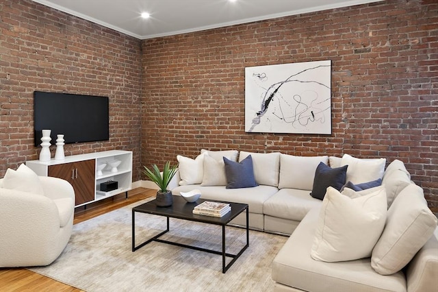 living room with wood finished floors, brick wall, and crown molding