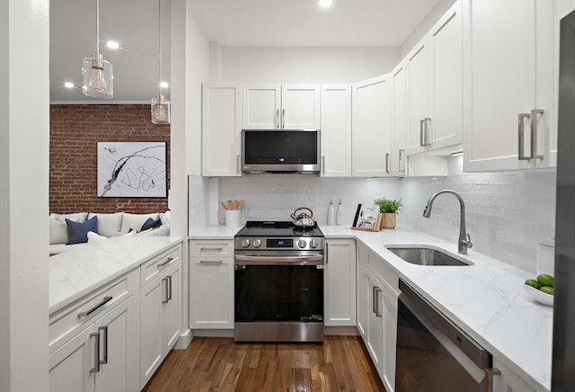 kitchen with light stone counters, white cabinetry, stainless steel appliances, and a sink