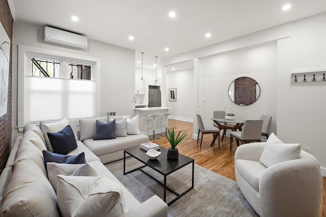 living area with light wood-type flooring, a wall mounted air conditioner, recessed lighting, and baseboards