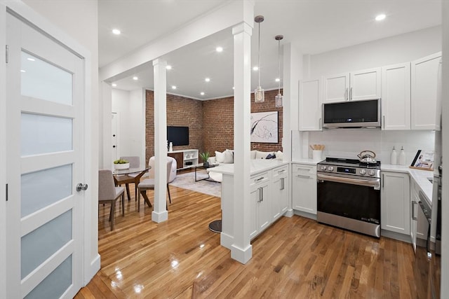 kitchen with light wood-type flooring, brick wall, stainless steel appliances, and ornate columns