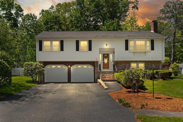 10 Lisa Ln, Reading, MA 01867 - bi-level home featuring asphalt driveway, a garage, and a chimney
