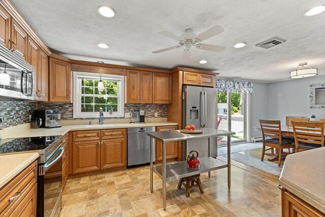 10 Lisa Ln, Reading, MA 01867 - kitchen with stainless steel appliances, decorative backsplash, brown cabinets, recessed lighting, and a ceiling fan