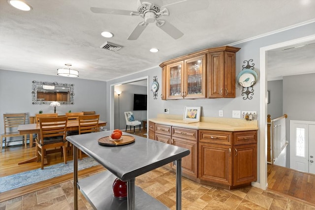 10 Lisa Ln, Reading, MA 01867 - kitchen with brown cabinetry, ceiling fan, light countertops, crown molding, and glass insert cabinets