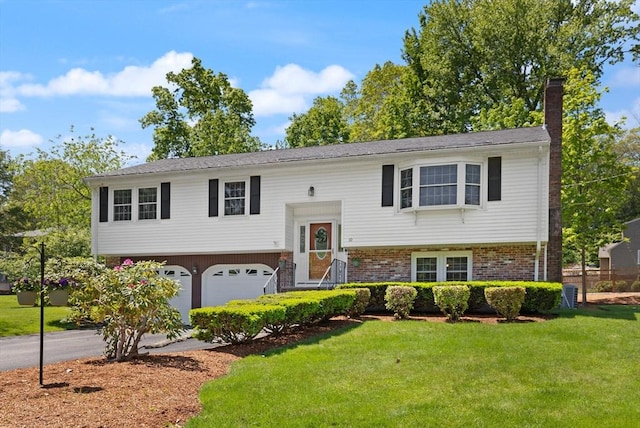 10 Lisa Ln, Reading, MA 01867 - bi-level home with a chimney, a garage, asphalt driveway, a front lawn, and brick siding