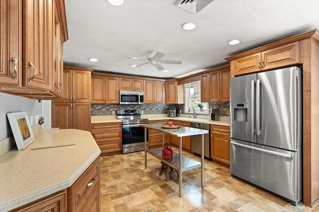 10 Lisa Ln, Reading, MA 01867 - kitchen featuring stainless steel appliances, brown cabinets, a ceiling fan, decorative backsplash, and recessed lighting