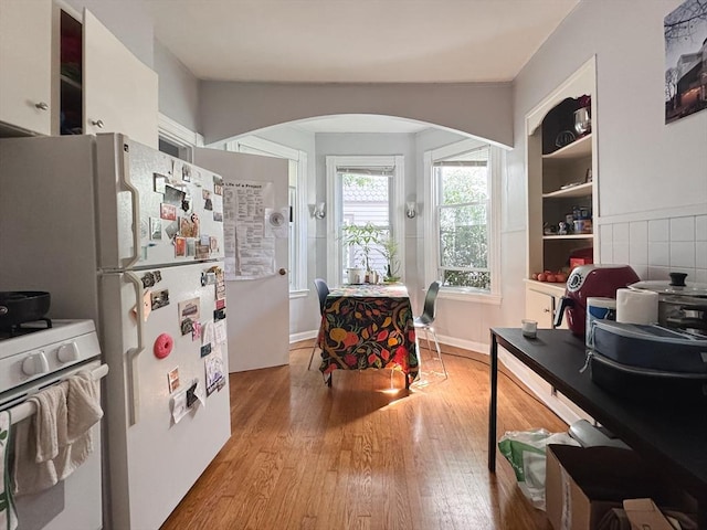 57 Bartlett St, Somerville, MA 02145 - kitchen with arched walkways, white appliances, and wood finished floors