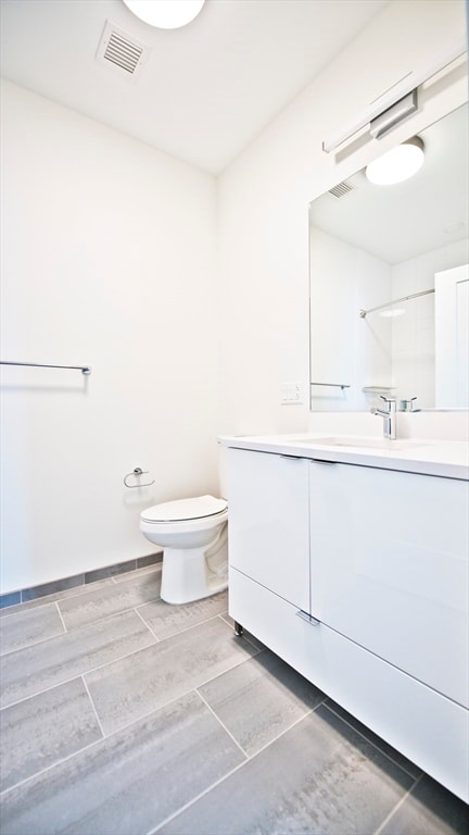 bathroom featuring vanity, walk in shower, and toilet