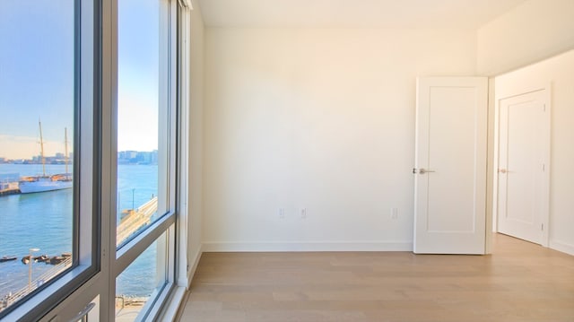 unfurnished room featuring a water view and light hardwood / wood-style floors