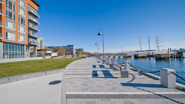 view of dock with a lawn, a water view, and a balcony