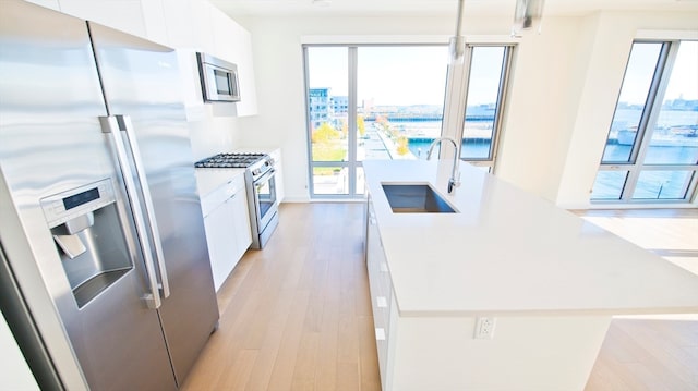 kitchen featuring a wealth of natural light, sink, appliances with stainless steel finishes, and white cabinetry