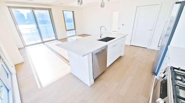 kitchen featuring a center island with sink, sink, white cabinets, and stainless steel appliances