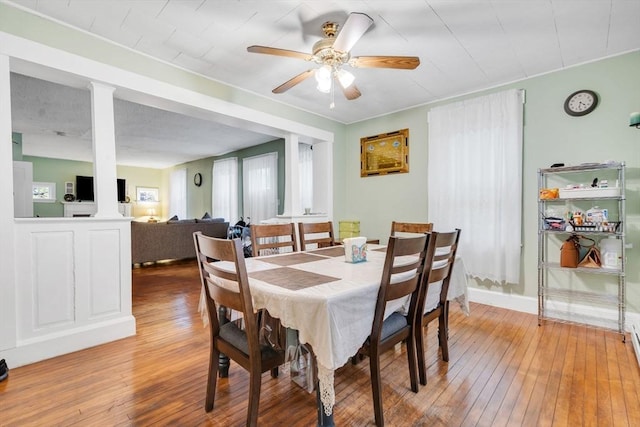 dining space with a ceiling fan, light wood-style flooring, and ornate columns
