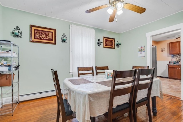 dining room with ceiling fan, a baseboard radiator, and light wood-type flooring
