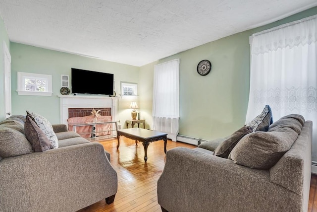 living room with hardwood / wood-style floors, a fireplace, a textured ceiling, and a baseboard radiator